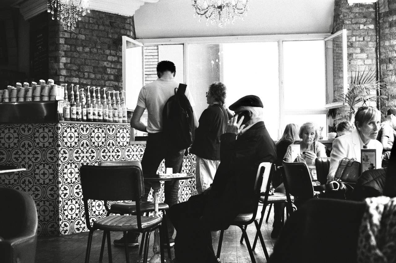 Old man using phone in coffee shop